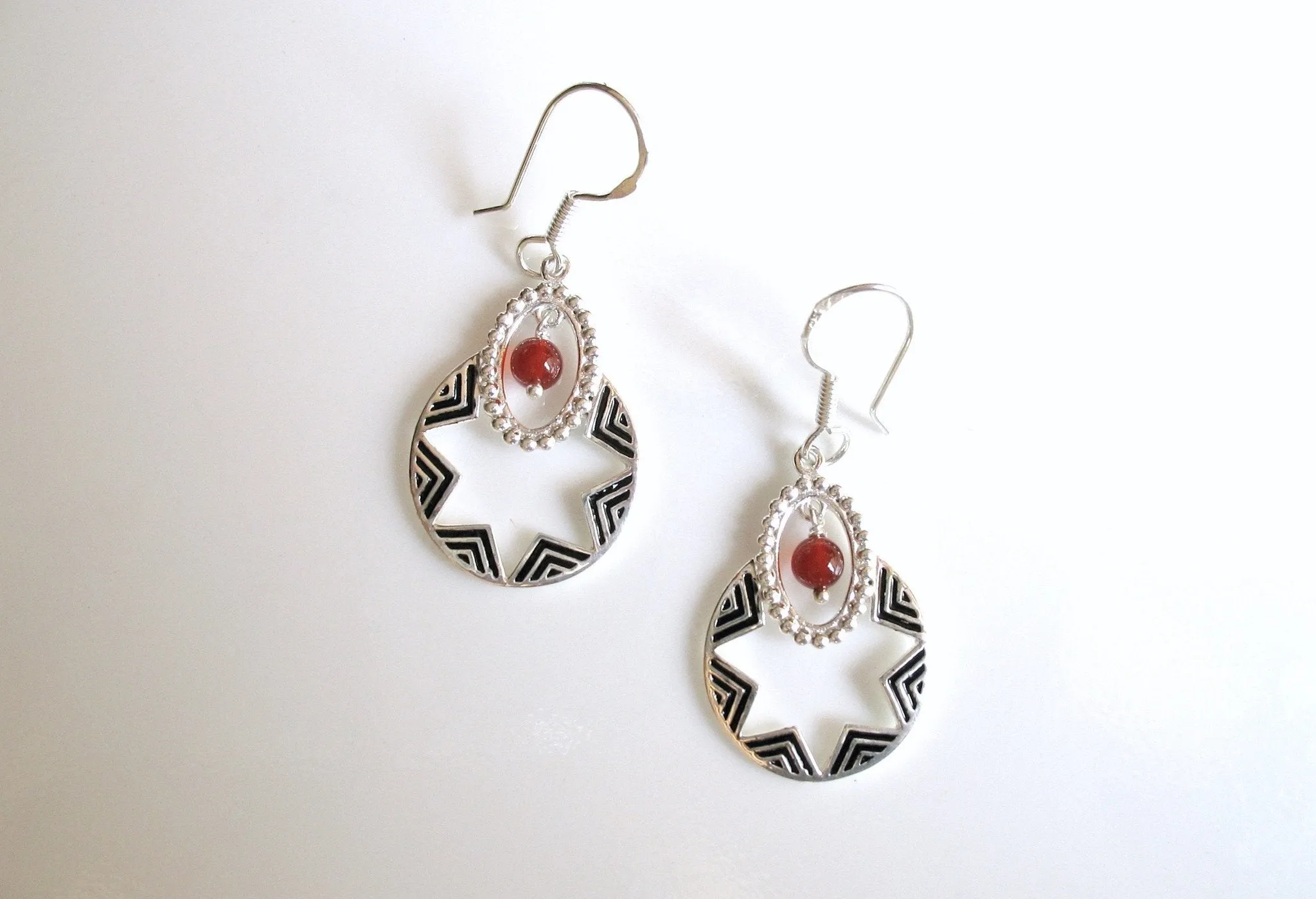 Quaint, oval dangling earrings with a garnet bead and fine black enamel work