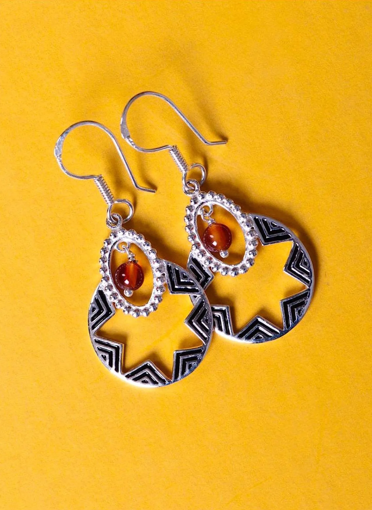 Quaint, oval dangling earrings with a garnet bead and fine black enamel work