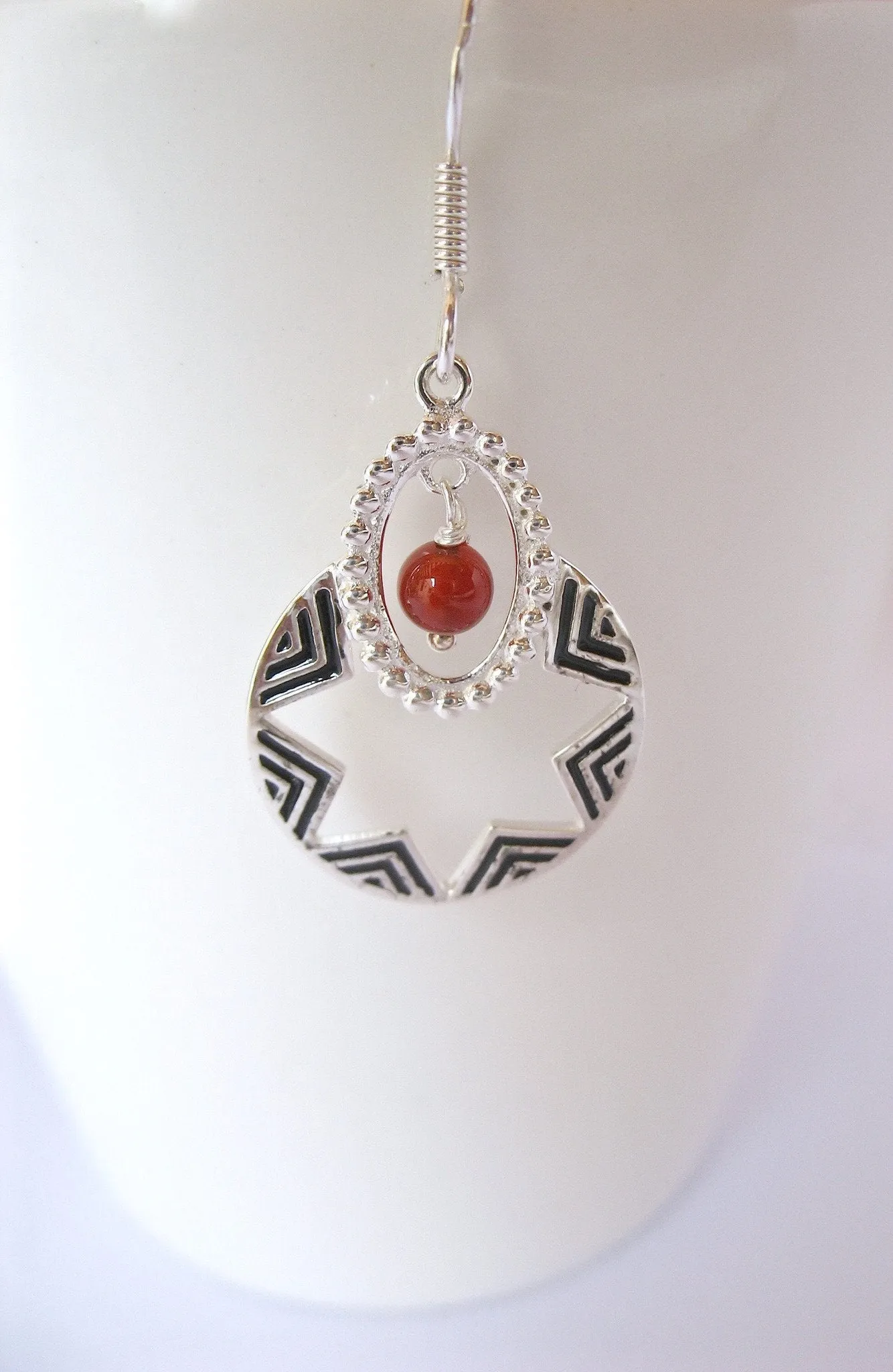 Quaint, oval dangling earrings with a garnet bead and fine black enamel work